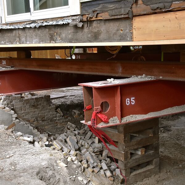 An old house rests on 65 foot long steel girders as a new concrete basement and foundation is being constructed.